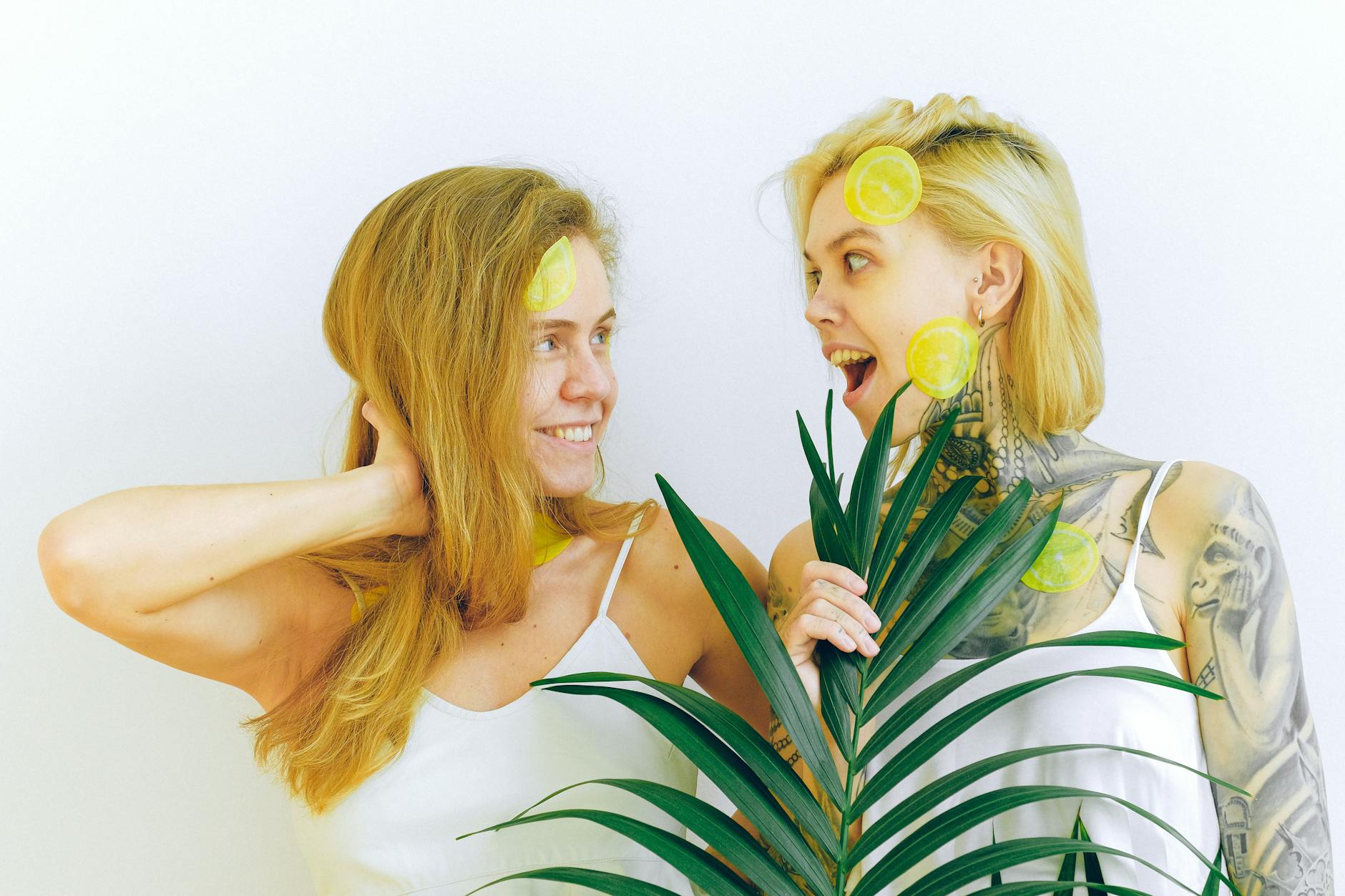 Blue vibrator surrounded by flowers and citrus on a bright yellow background