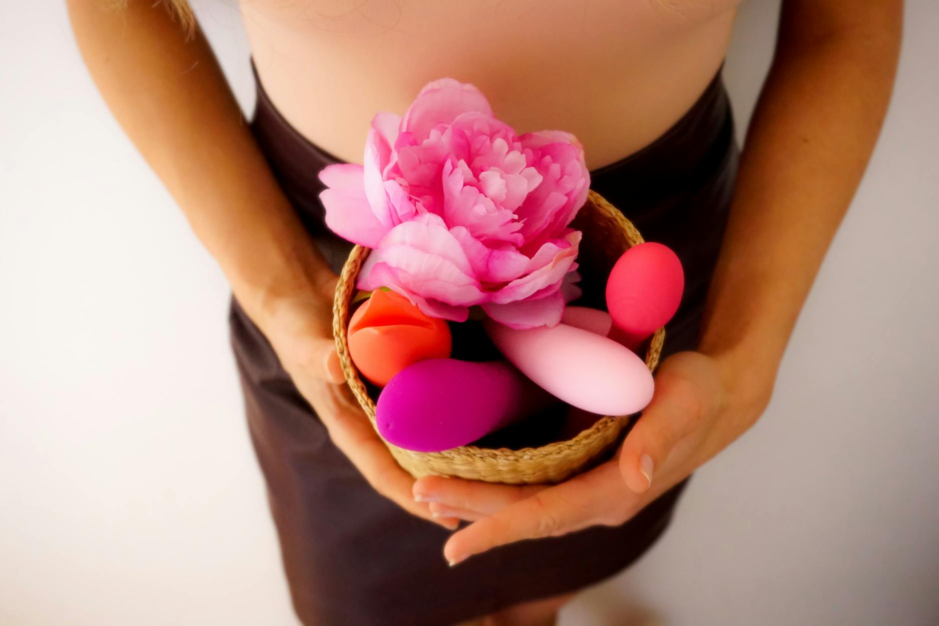 A close-up of a hand holding an orange vibrator against a minimalistic purple backdrop, showcasing modern sensuality.
