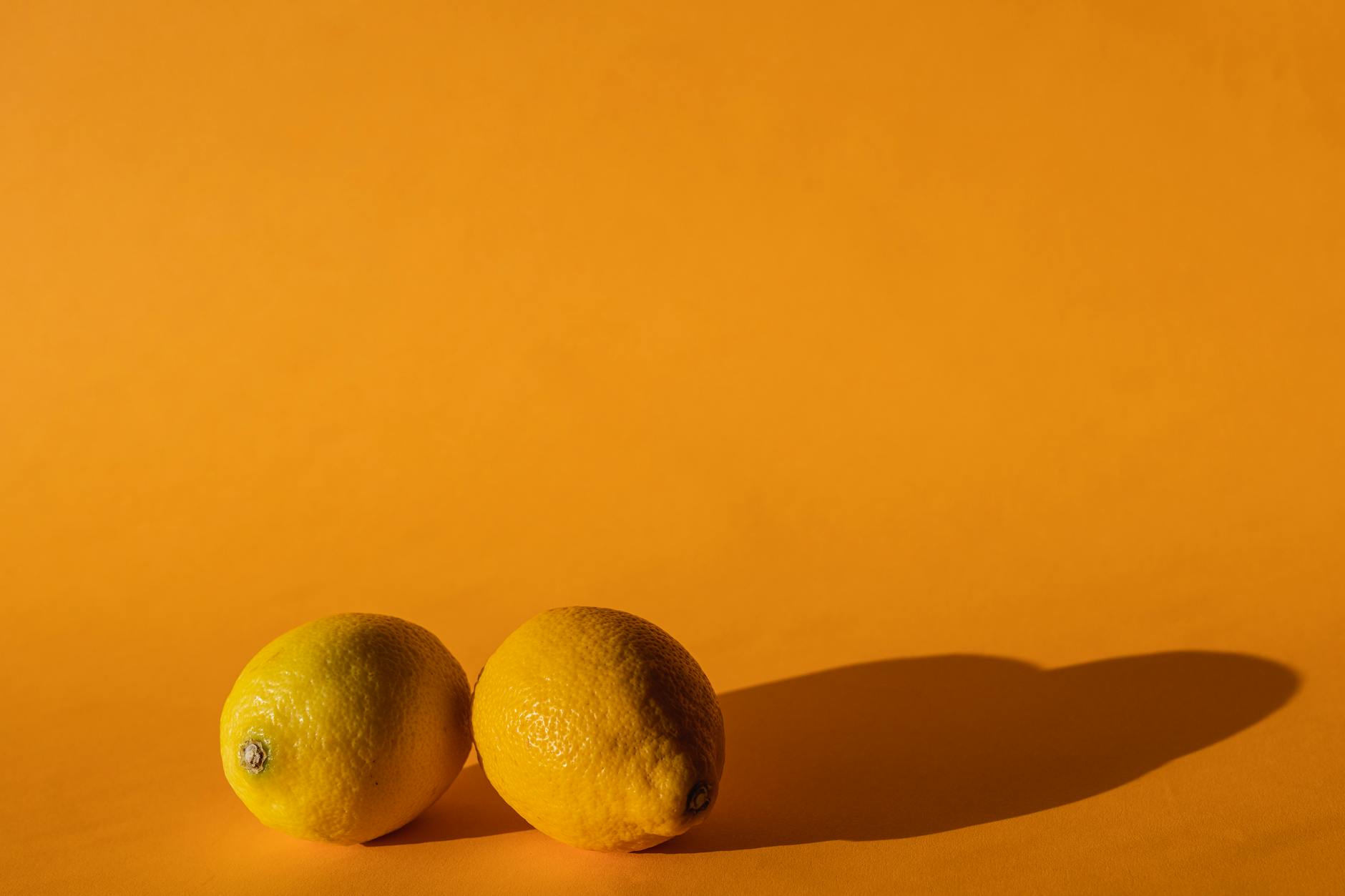 Fresh lemons arranged on a yellow background in bright daylight